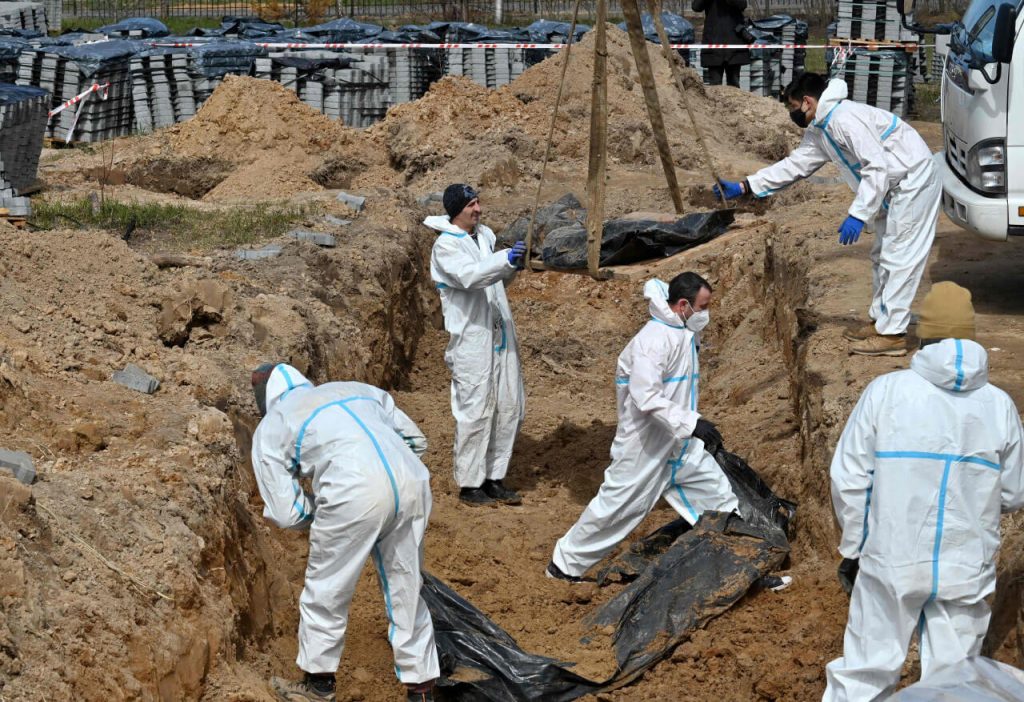 Рабочие эксгумируют тела массового захоронения в городе Буча