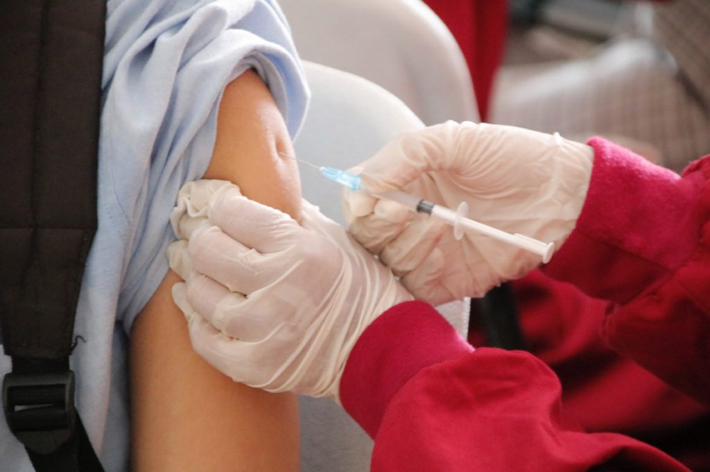 Грипп, фотография, иллюстрирующая то, как врач ставит прививку в плечо пациенту