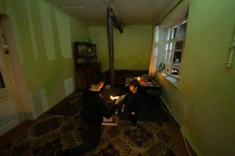 Двое мальчиков топят печь, чтобы согреться, сидя дома в Степанакерте