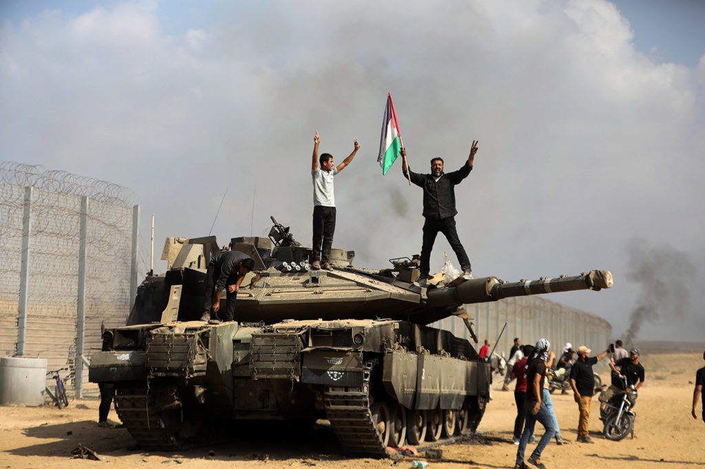 ХАМАС напал на Израиль. Палестинцы на подбитом израильском танке у забора рядом с границей Израиля и Сектора Газа, 7 октября 2023.