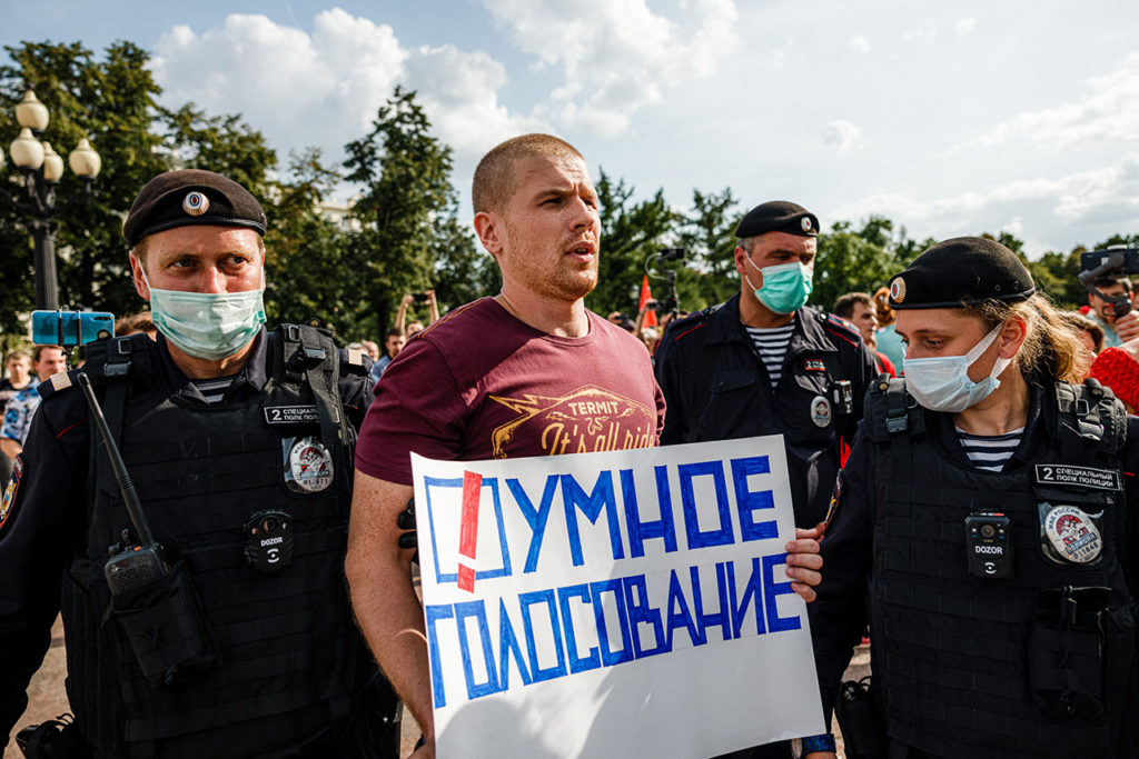 Сотрудники полиции задерживают мужчину с плакатом «Умное голосование» во время акции протеста в Москве 14 августа 2021 г.