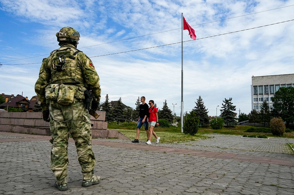 Годовщина освобождения Херсона. Молодая пара проходит мимо российского военного на главной площади Херсона. 20 мая 2022 года. Фото: AP / Scanpix