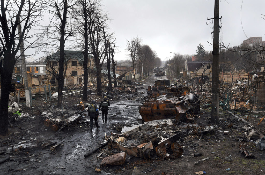 Украинские полицейские идут между разбитой военной техникой в Киевской области, Украина. 