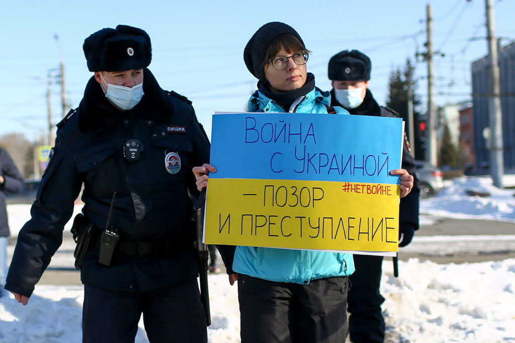 Полиция задерживает протестующую с плакатом «Война с Украиной — позор и преступление» в Омске, 27 февраля 2022 года.