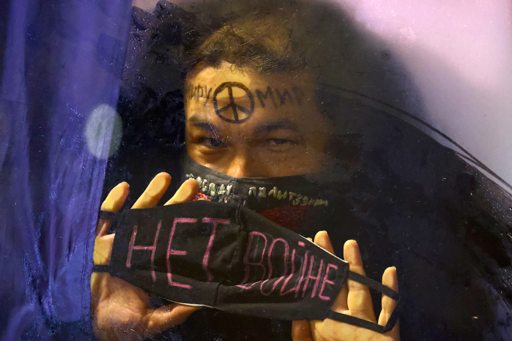 Задержанный показывает маску с надписью «Нет войне» в полицейской машине во время антивоенного протеста в Санкт-Петербурге, 24 февраля 2022 года.