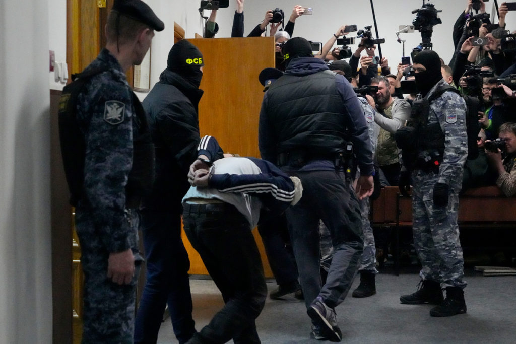 Подозреваемого в стрельбе в «Крокус Сити Холл» сотрудники полиции выводят из зала суда в Москве, 24 марта 2024 года.
