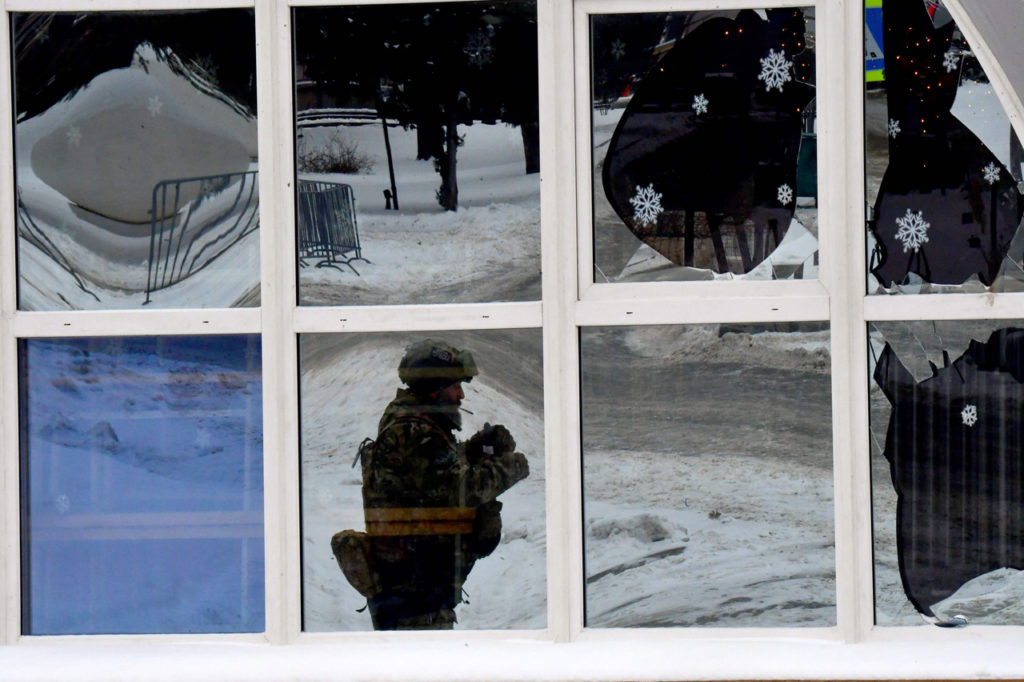 «Снежинки» на окнах в центре города на фоне добровольца отряда территориальной обороны, 10 января 2024 года