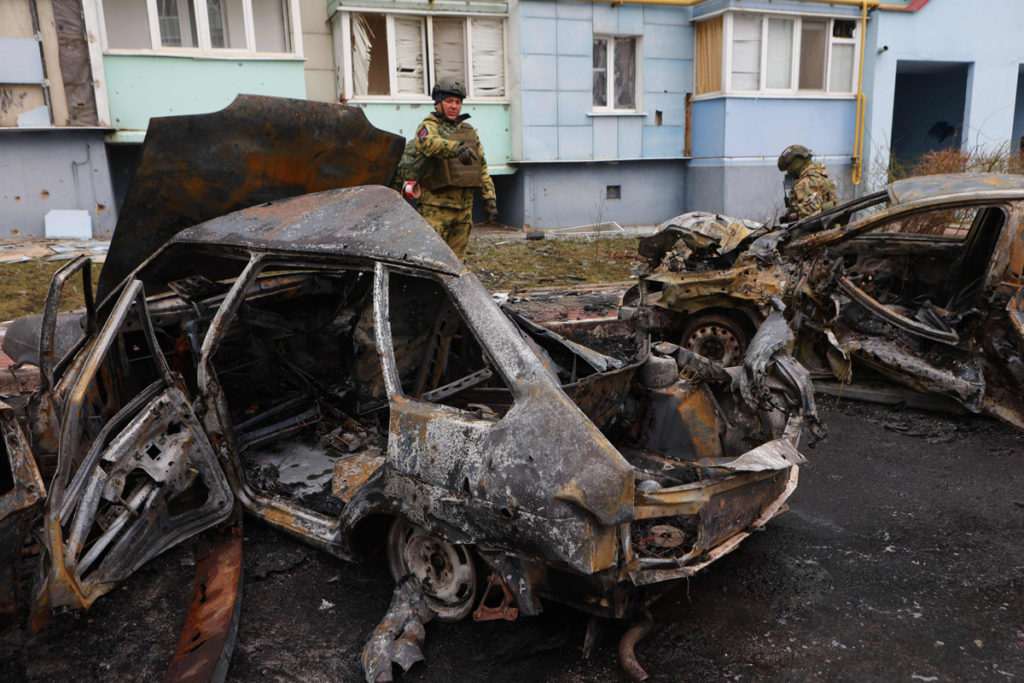 Добровольцы отряда самообороны стоят у сгоревших автомобилей в жилом районе Белгород после авиаударов по городу, 22 марта 2024 года.